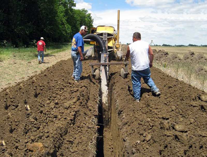 workmen installing drainage tile in an agricultural field