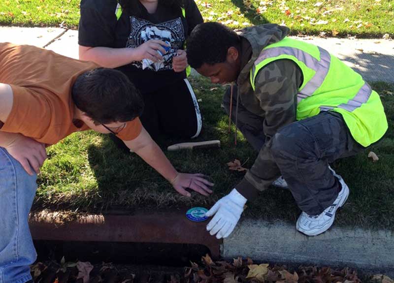 Students place "do not dump" stickers on storm grates in Powell, Ohio.