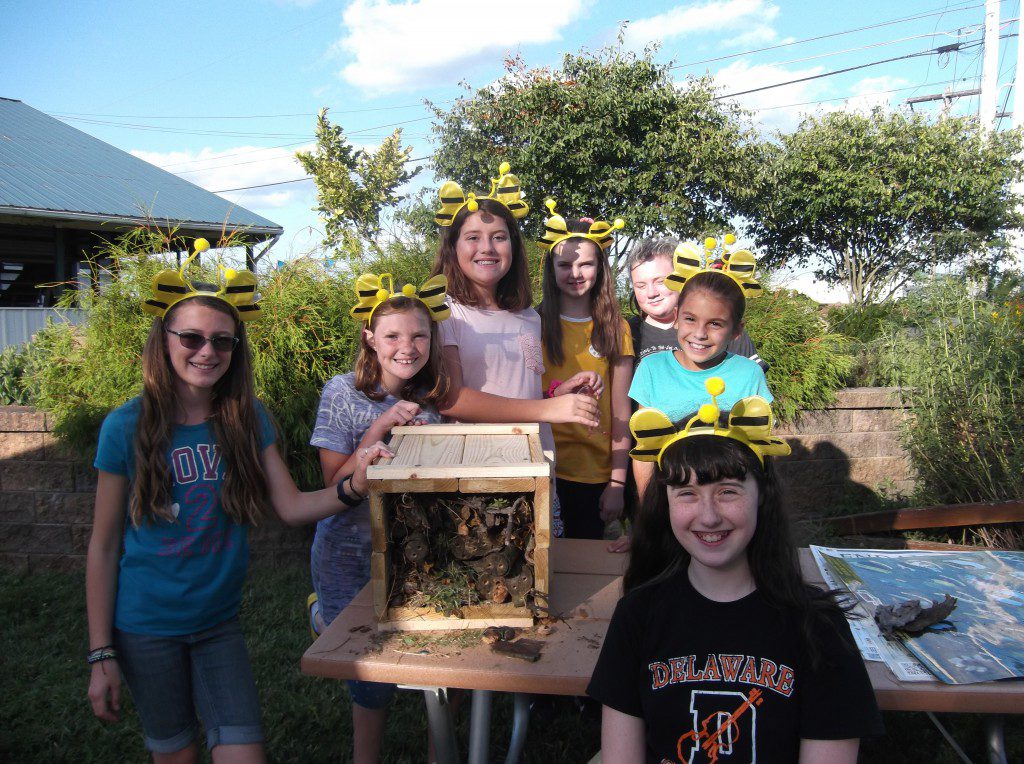 Girl Scouts standing around a bee hotel they built.